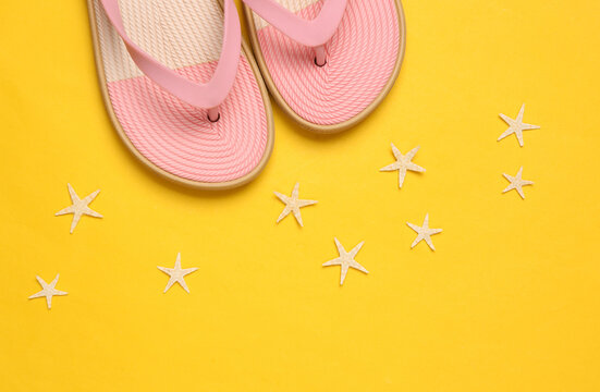 Colored flip flops with sea stars on blue-pink pastel background. Beach vacation concept. Flat lay