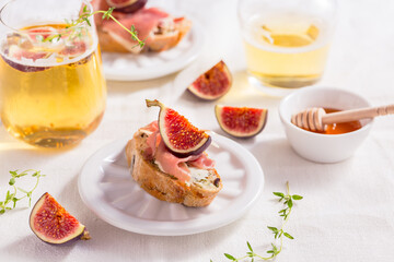 Obraz na płótnie Canvas Small canape snack, crostini with ham, fig and apple wine