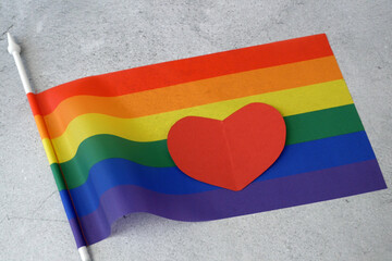 Rainbow flag as LGBT gay symbol and heart shape as love sign on gray background