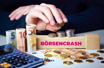 Börsencrash - Börsenkrach. Hand baut Geldstapel auf einem Baustein mit Text. Turm aus Euro...