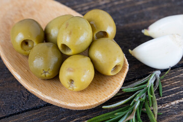olives with spices and rosemary in a wooden spoon