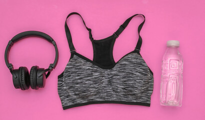 Sports top bra, bottle water and stereo headphones on pink background. Sport and fitness. Getting ready for training. Top view. Flat lay