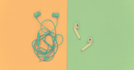 Wireless earphones and wired tangled headphones on yellow background. Top view. Flat lay