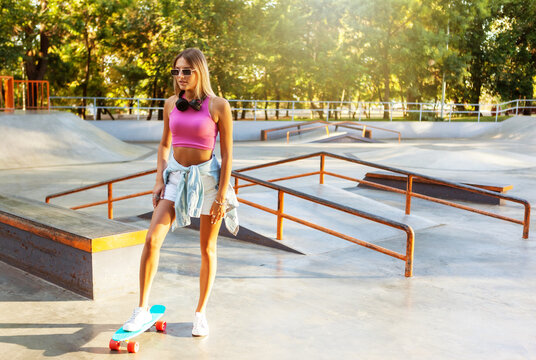 Image of young stylish woman skater with cruiser board on skate park