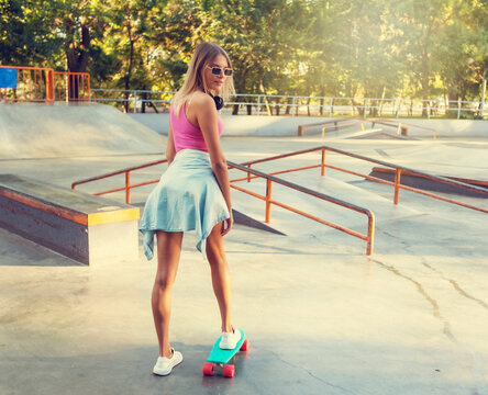 Image of young stylish woman skater with cruiser board on skate park