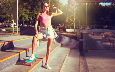 Funny stylish young woman skater with cruiser board and retro 80s tape recorder in skatepark © splitov27