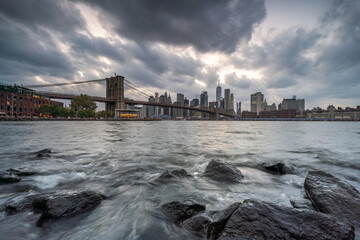 Brooklyn Bridge and Manhattan skyline along the East River on a cloudy day, New York City, USA