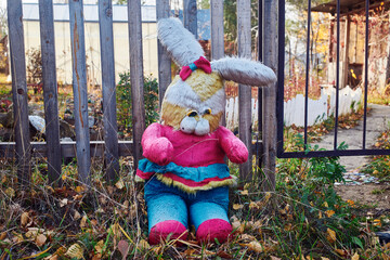 An old abandoned toy near the fence. A big bright plush rabbit.
