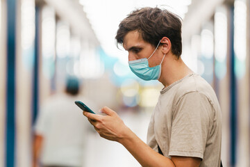 Young white man wearing face mask using mobile phone