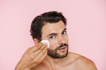 White shirtless man applying concealer with cotton pad