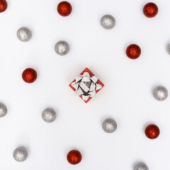 Christmas composition with red and silver shiny balls and gift box with surprise on white New Year holiday pattern