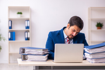 Young male employee unhappy with excessive work in the office