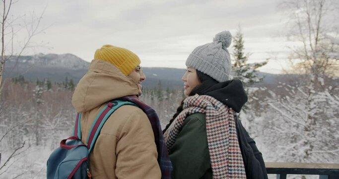 Man and woman watching mountains in winter enjoying outdoor date hugging expressing love. Romantic relationship and tourism concept.
