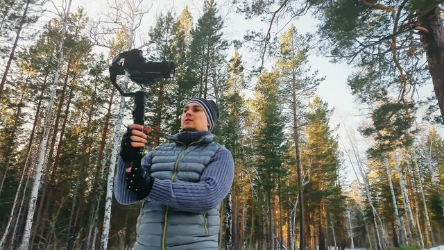 Professional Videographer Holding DSLR Camera on 3-axis Gimbal Stabilization Device in Winter. Pro Equipment Helps to Make High Quality Video Without Shaking. Cinematographer Operator. Slow Motion