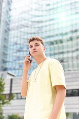 Young man in yellow T-shirt talking on the phone in the street