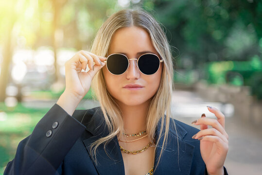 Portrait Of A Beautiful Blonde Woman Putting On Sunglasses