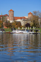 Wawel Royal Castle, view from the side of the Wisla river on an autumn day, barges and restaurants,...