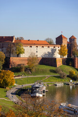 Wawel Royal Castle, view from the side of the Wisla river on an autumn day, barges and restaurants,...