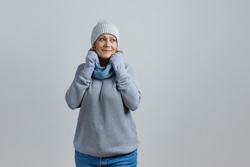 mature woman in a gray sweater and knitted hat wrapped herself in a scarf from the cold. Isolated...