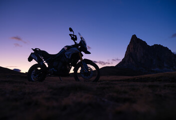 The silhouette of a motorcycle against the backdrop of mountains and sunset. Travel and adventure on a motorcycle in the mountains. Sports and outdoor activities. Photo in high resolution..