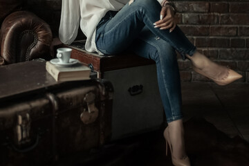 Fototapeta na wymiar Elegant woman in slim blue jeans sitting with her legs crossed