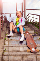 Lifestyle Concepts. Caucasian Female  Skateboarder Posing With Longboard On Stairways Outdoor Environment While Sitting on Stairs