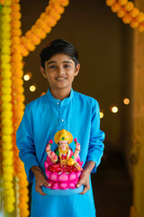 Cute Indian little boy holding goddess laxmi sclupture in hand and celebrate diwali festival.