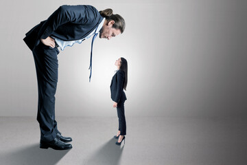 Businessman looking down on female subordinate on concrete background with mock up place for your...