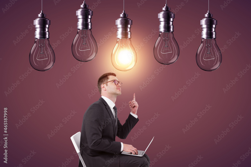 Poster Young european businessman using laptop and pointing at abstract glowing row of light bulbs on red background. Idea, solution and innovation concept.
