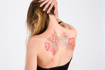 Obraz premium Closeup of Brunette Woman Back With Flowery Tattoes Posing in Sexy Black Body With Tilted Shoulders Over White.