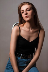 Naklejka premium Alluring Caucasian Blond Girl With Long Beautiful Hair Posing on Ladder in Studio Against Dark Background.