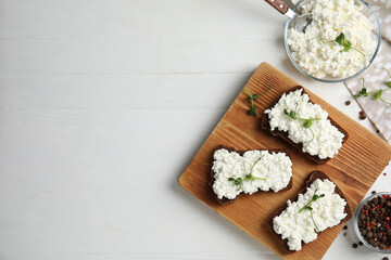 Obraz na płótnie Canvas Bread with cottage cheese and microgreens on white wooden table, flat lay. Space for text