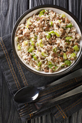 Dirty rice is a traditional Louisiana Creole dish made from white rice cooked with Ground beef, liver, green bell pepper, celery, and onion close-up in a plate on the table. Vertical top view
