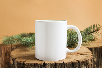 White mug on a wooden stand with fir branches front view. Mockup for print, copy space and advertising.
