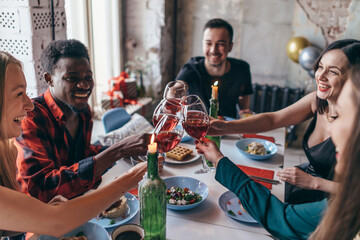 Friends sitting at table drinking wine clinking glasses