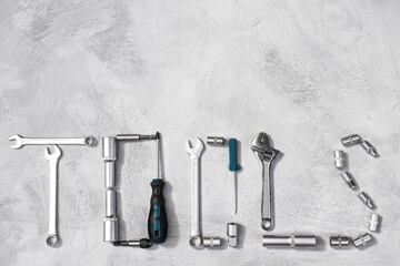 Automotive tools collected in an inscription on a gray concrete background top view. Wrenches, screwdrivers, silver colored bits for repair and work.