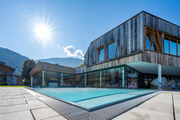 modern pool building with weathered wood facade with fresh turquoise water and sunbeams