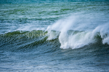 Beautiful early morning ocean waves with spray been blown by strong winds.