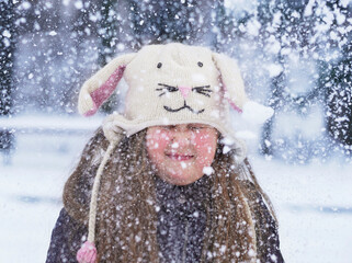  Smiling funny Little girl with long hair wearing in funny knitted hat with long rabbit Ears...