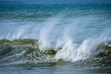 Beautiful early morning ocean waves with spray been blown by strong winds.