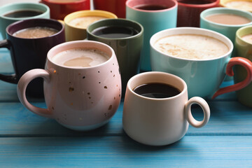 Many cups of different coffee drinks on light blue wooden table