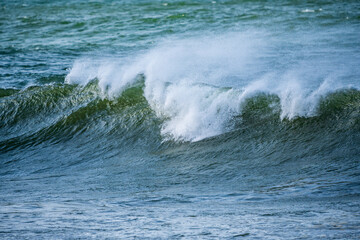 Beautiful early morning ocean waves with spray been blown by strong winds.