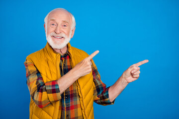 Portrait of attractive cheerful grey-haired man demonstrating copy empty blank space isolated over bright blue color background