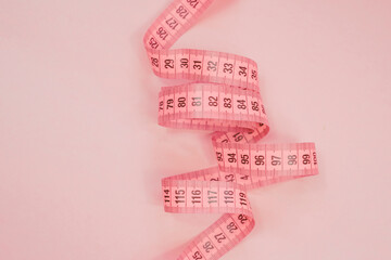 Measure tape on the pastel pink background. Mock up for body slimming, weight loss or dressmaker's...