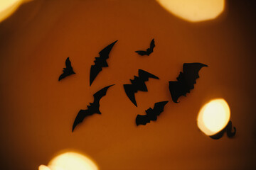 Halloween background. Bats flying on dark orange background with magical lights. Happy Halloween
