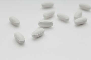 white tablet pills on white blurred background, selective focus