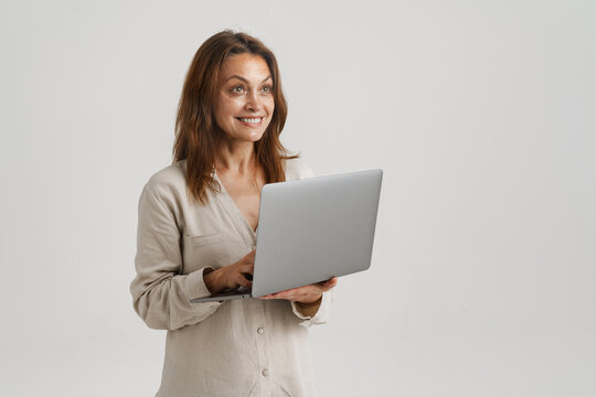European ginger woman smiling while using laptop