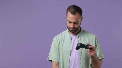 Sad boring†excited happy fun young bearded man 20s wears mint shirt hold in hand play pc game with joystick console take mobile cell phone go isolated on plain light purple background studio portrait