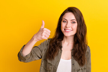 Portrait of charming cheerful lady toothy smile show thumb up look camera isolated on yellow color background