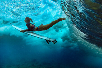 Mid adult woman with surfboard swimming underwater